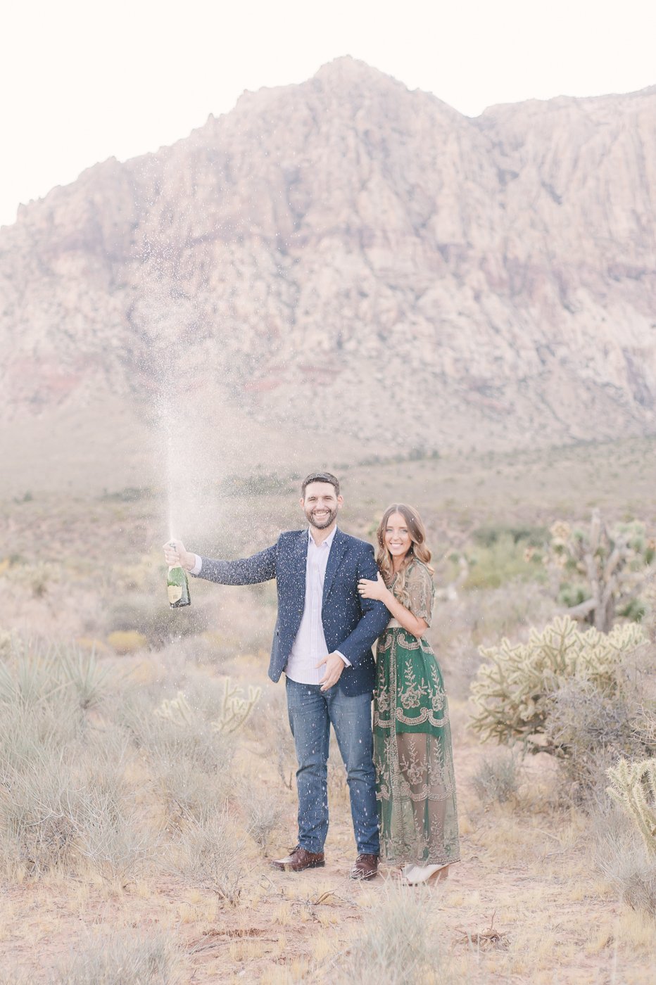 engaged couple spraying champagne in the desert