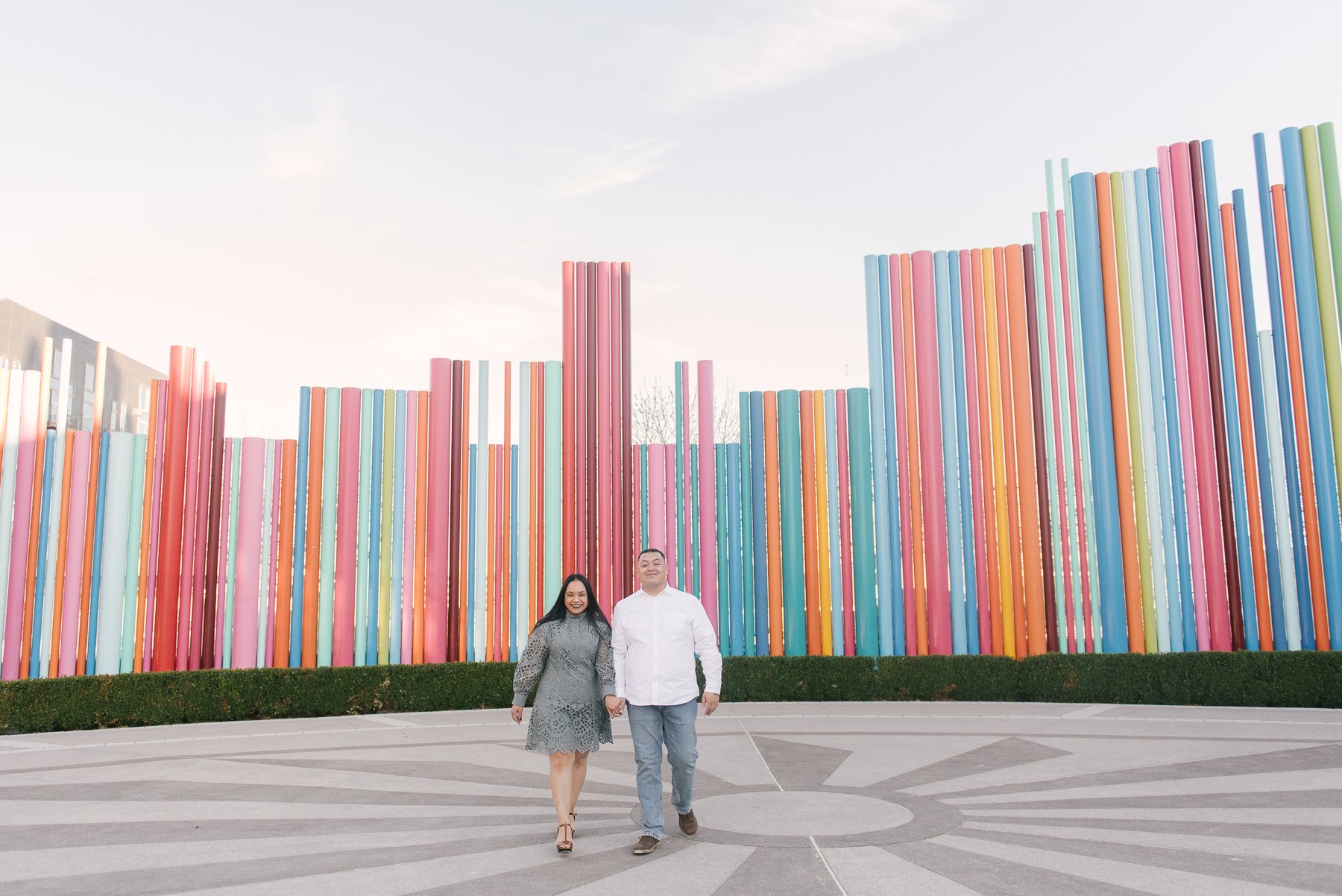 couple walking in front of rainbow art sculpture