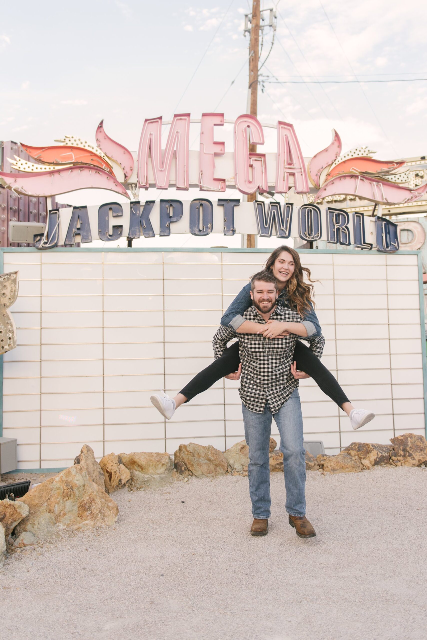 couple piggy back ride in front of jackpot sign