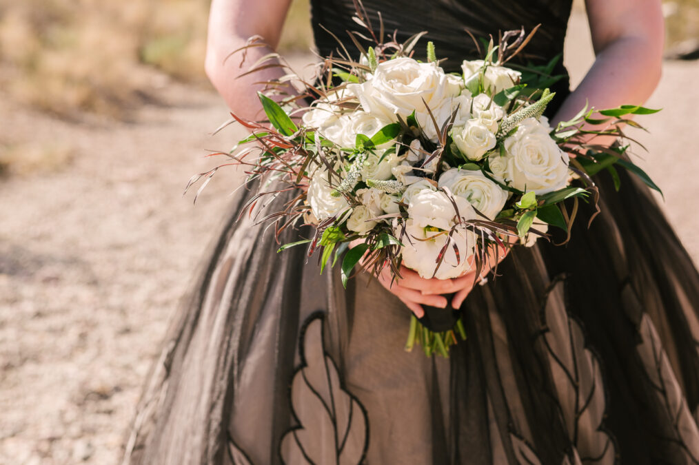 close up of alternative floral bouquet against black wedding dress 