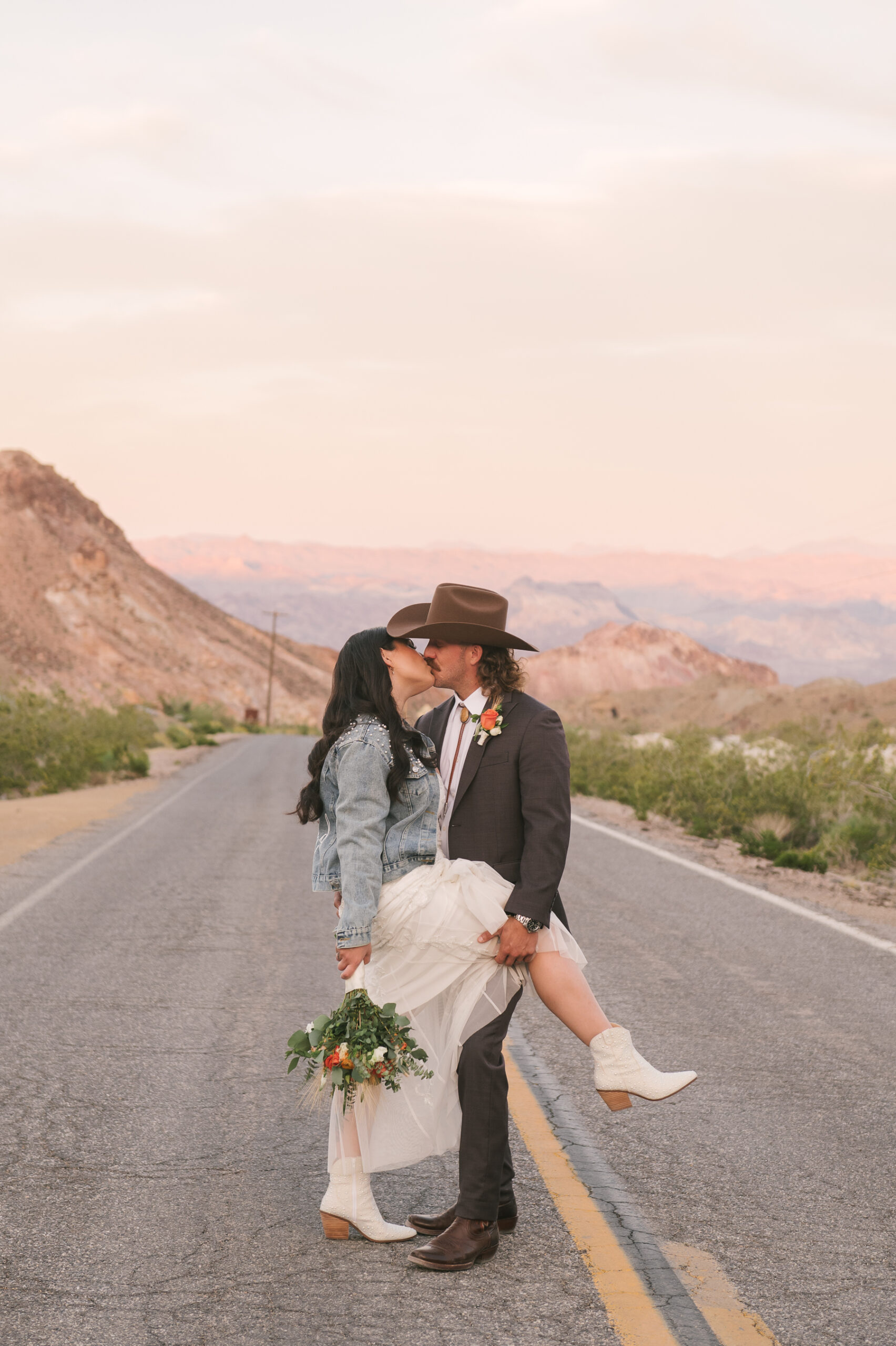 couple kissing in the middle of the road with sunset in the background