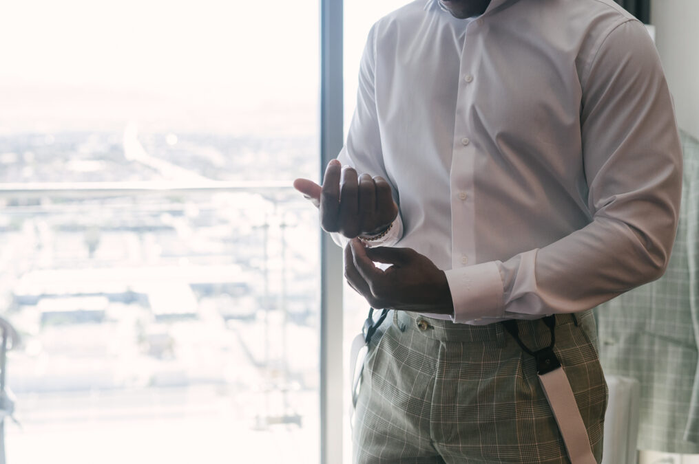 groom buttoning shirt while getting ready