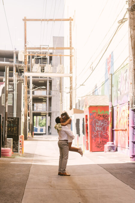 groom carries his bride along graffiti alley in downtown las vegas