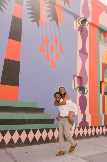 groom gives bride a piggy back ride along graffiti wall in downtown las vegas