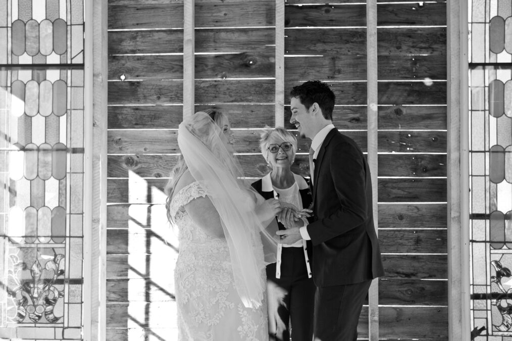 black and white image of bride and groom smiling during their ceremony at nelson ghost town