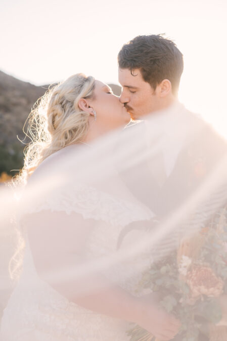 las vegas bride and groom kissing with veil in front