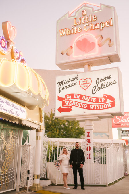 Vintage Las Vegas bride and groom in front of little white chapel neon sign