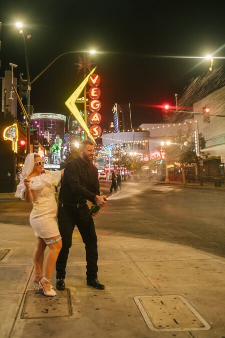 Bride and Groom popping champagne in front of Vegas sign on Fremont Street 