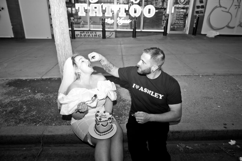 downtown las vegas bride and groom eating cake on the sidewalk