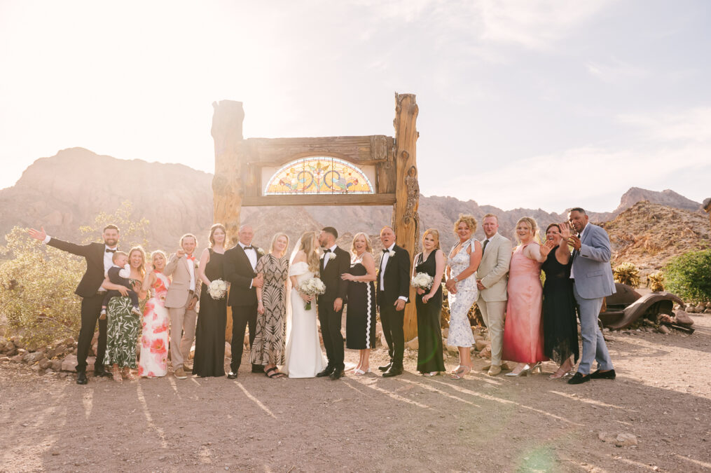 UK destination bride and groom in front of stained glass arch in the las vegas desert with guests 