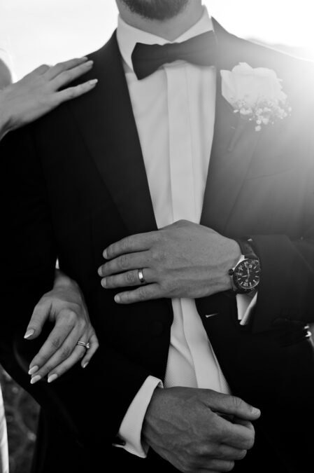 black and white close up of groom's tux and wedding rings