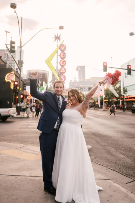 bride and groom celebrating in front of vegas sign on fremont street