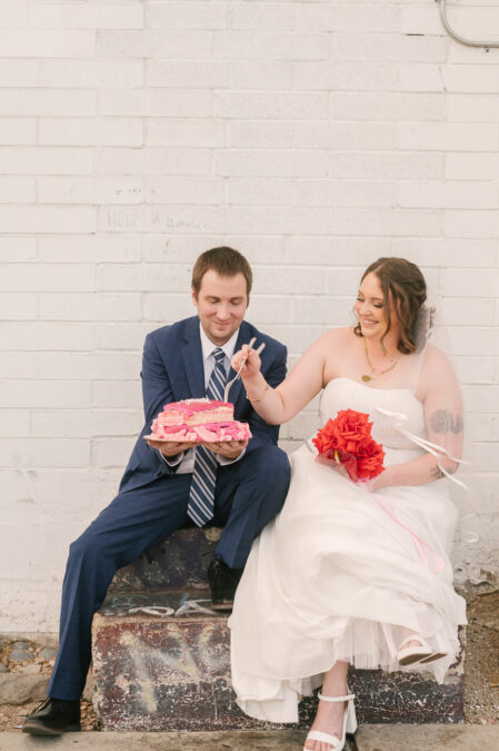 las vegas bride and groom eating cake on the sidewalk 