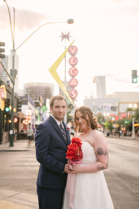 bride and groom posing in front of vegas sign on fremont street
