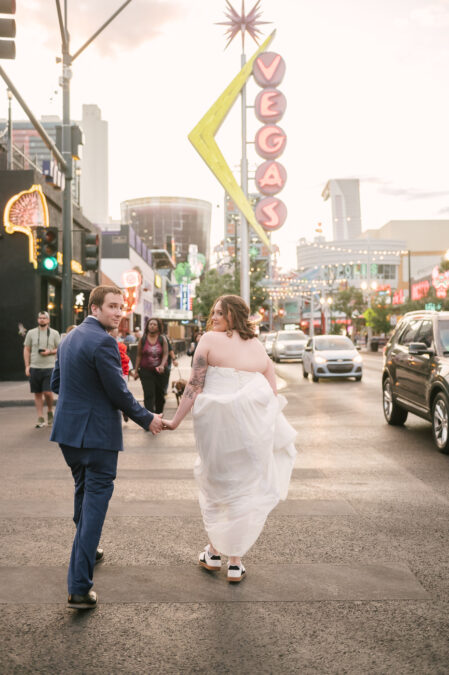 bride and groom walking in front of vegas sign on fremont street