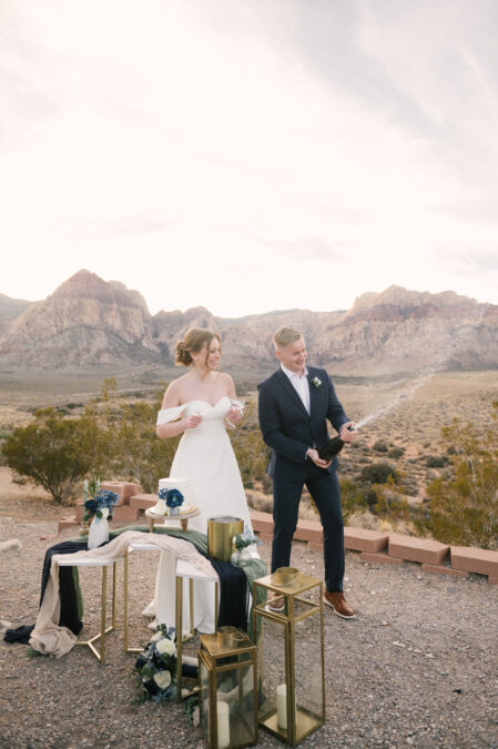 bride and groom celebrating with champagne spray and cake at red rock canyon las vegas