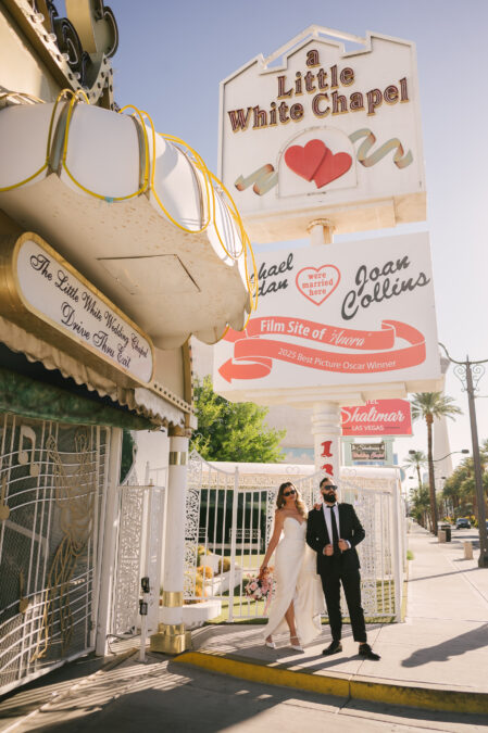 bride and groom posing in front of little white chapel