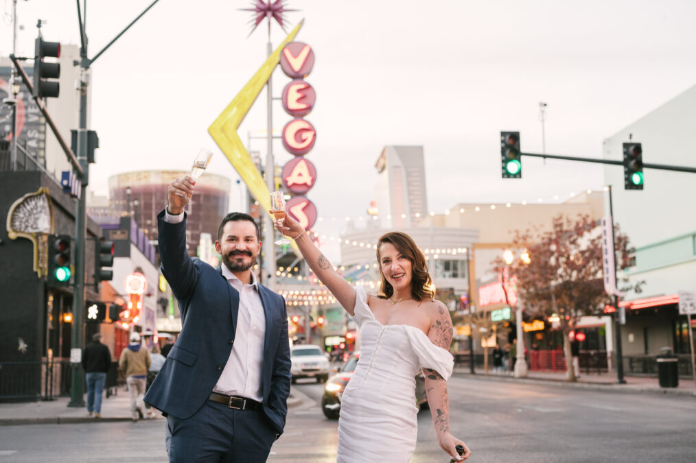 bride and groom with champagne in front of the downtown vegas sign on fremont street