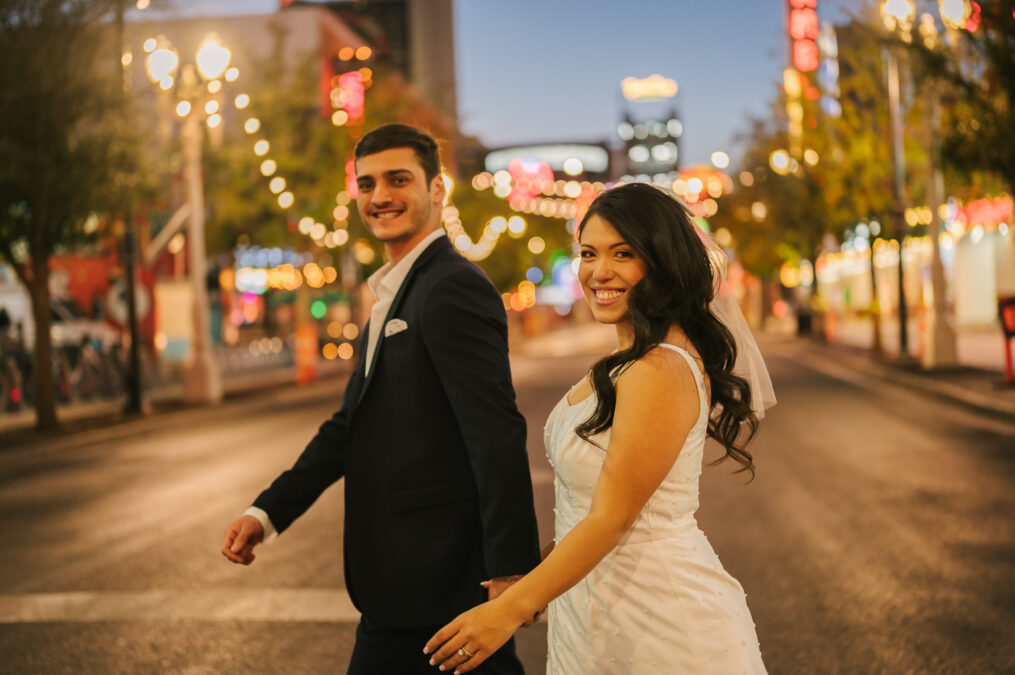 bride and groom walking with Las Vegas fremont street lights in the background 